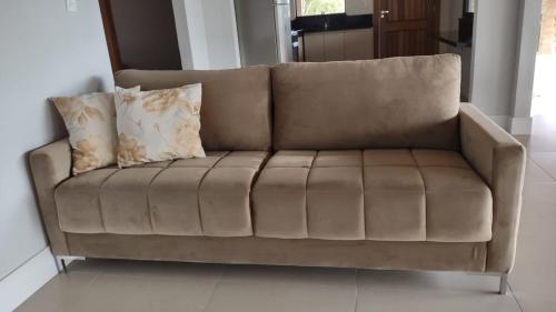 a brown couch with two pillows on top of it at Laggus Residencial Náutico in Ferraria