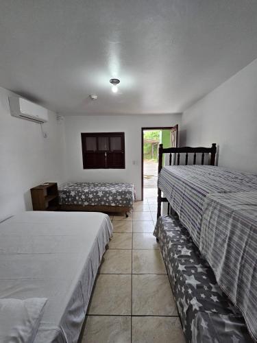 um quarto com duas camas e uma televisão na parede em Pousada Recanto das Ondas em Garopaba