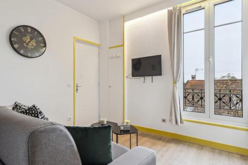ein Wohnzimmer mit einem Sofa und einer Uhr an der Wand in der Unterkunft Unique Apartment for 4 - Paris & Disney in Champigny-sur-Marne