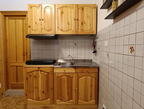 a kitchen with wooden cabinets and a sink at Collalto Guest House in Piancavallo