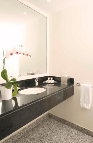 a bathroom with a sink and a large mirror at Hilton Colon Guayaquil Hotel in Guayaquil