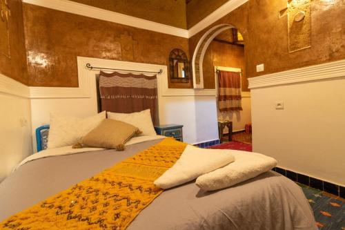 a bedroom with a bed with an orange blanket on it at Kasbah Assafar in Kalaat MGouna