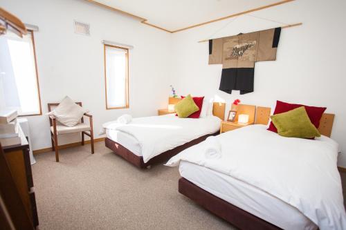 a room with two beds and a chair in it at Yume House in Niseko