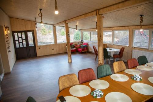 uma sala de jantar com mesas, cadeiras e janelas em Casa Pop em Câmpulung