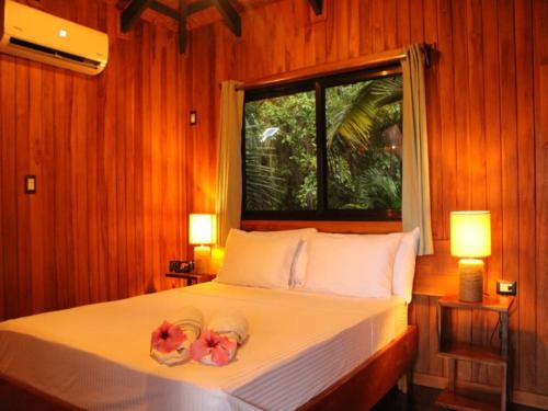 ein Schlafzimmer mit einem Bett mit zwei Blumen drauf in der Unterkunft Natural Drake Bay Hotel Boutique in Drake