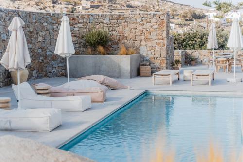 a swimming pool with chairs and umbrellas next to a resort at Oliving Mykonos Luxury Suites in Klouvas