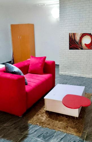 a living room with a red couch and a coffee table at Spacious studio apartment in Lekki