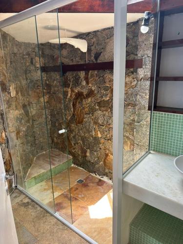 a shower in a bathroom with a stone wall at Pousada Vista Grega in Arraial do Cabo