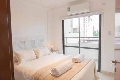 - une chambre blanche avec un lit et une fenêtre dans l'établissement Torre Alem 4 A, à San Miguel de Tucumán