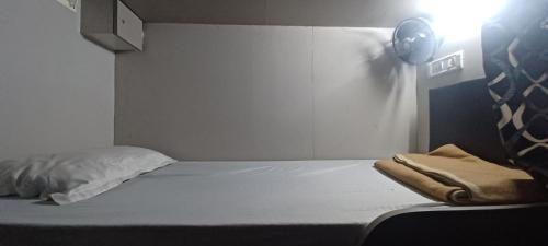 a bedroom with a white bed with a spotlight at New Passenger Dormitory in Mumbai