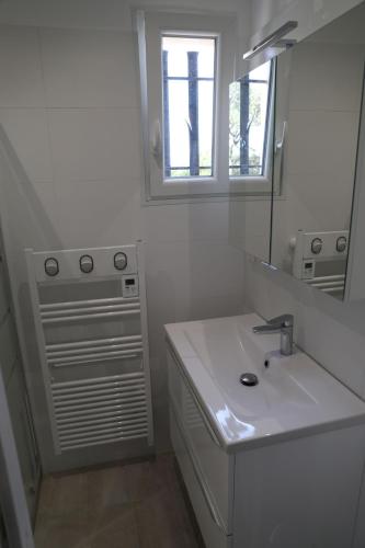 une salle de bain blanche avec un lavabo et un miroir dans l'établissement MOULIN a VENT 3429, aux Issambres