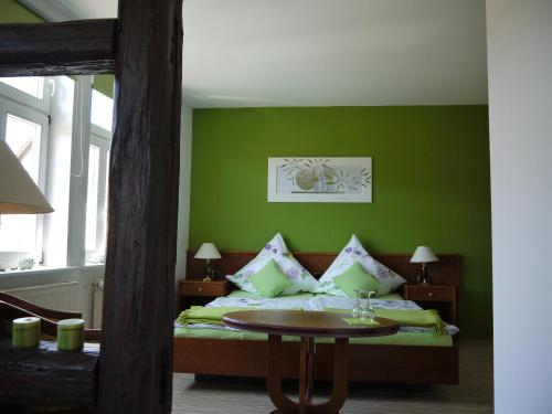a bedroom with a bed with green walls and a table at Ilsenburger Hof - NEUER BETREIBER in Ilsenburg