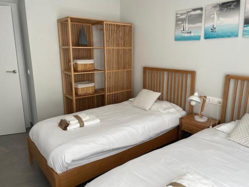 2 aparte bedden in een kamer met een boekenplank bij Sunny penthouse beach apartment with panoramic views in Almuñécar