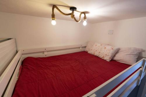 Bett in einem Zimmer mit einer roten Decke in der Unterkunft Rifugio a 15min dalle piste da sci in Frabosa Sottana