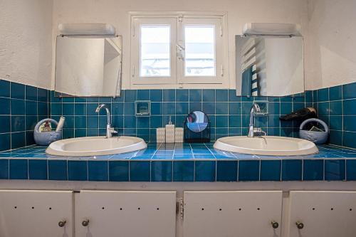 two sinks in a blue tiled bathroom with two mirrors at La Maison et son jardin clos in Porquerolles