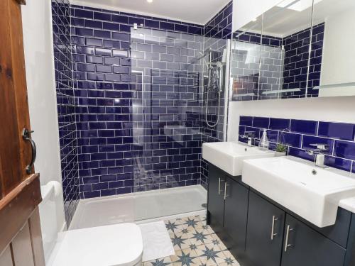 ein blau gefliestes Bad mit 2 Waschbecken und einer Dusche in der Unterkunft Palm Tree Cottage in Sandown