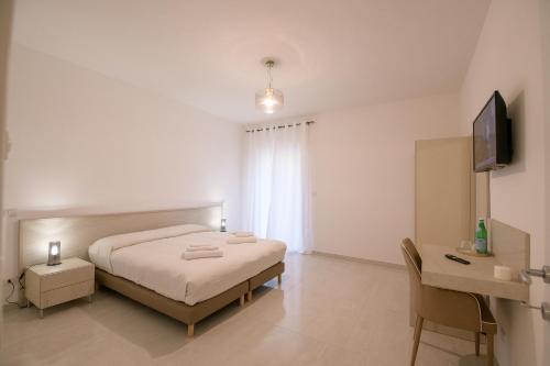 a white bedroom with a bed and a television at A Due Passi in Montesano Scalo