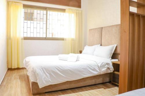a bedroom with a bed with white sheets and a window at Rabat Ville in Rabat