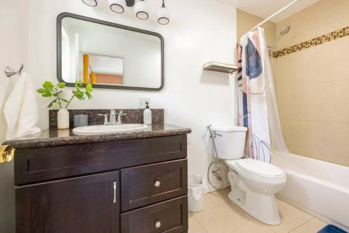 W łazience znajduje się umywalka, toaleta i lustro. w obiekcie Emerald Guest House w mieście San Diego