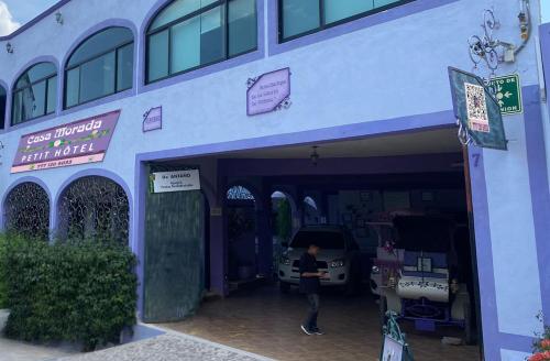 een vrouw staat buiten een blauw gebouw bij Casa Morada in Bernal