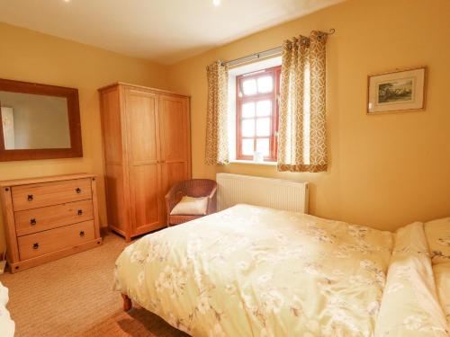 a bedroom with a bed and a dresser and a window at Ratty's Retreat in Spilsby