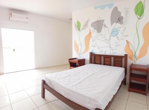 een slaapkamer met een bed en een muur met bloemen bij Casa para temporada c/ ar condicionado, próximo da praia e do Beco das Garrafas in Prado