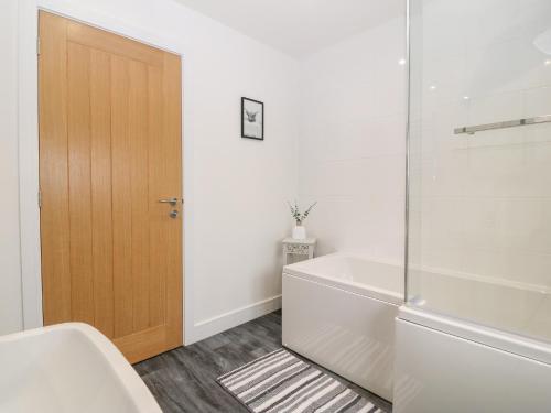 a bathroom with a tub and a glass door at White Bull House in Amlwch