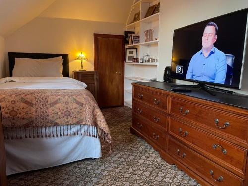a bedroom with a bed and a flat screen tv on a dresser at Ramadale Stornoway in Stornoway