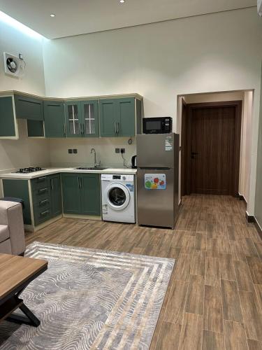 a kitchen with green cabinets and a washer and dryer at سكن التميز للإيجار (وحدات سكنية مفروشة) in Al-Salam