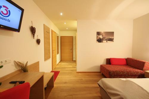 a living room with two red chairs and a tv at Landhotel Laudersbach in Altenmarkt im Pongau