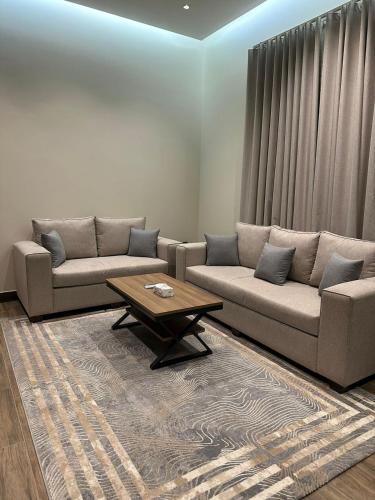 uma sala de estar com dois sofás e uma mesa de centro em سكن التميز للإيجار (وحدات سكنية مفروشة) em Al-Salam