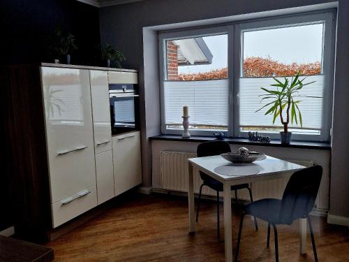 a kitchen with a table and two chairs and two windows at Moorparadies FRI-Südliches Friesland in Bockhorn