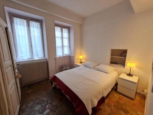 een slaapkamer met een groot bed en 2 ramen bij Le Jeu de Paume à Beaune centre in Beaune