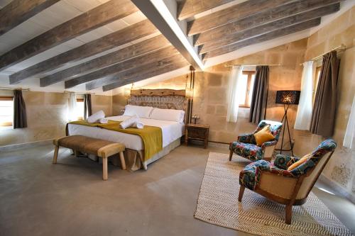 a bedroom with a large bed and two chairs at Calvario Plaza Hotel in Pollença