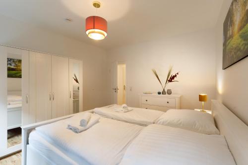- une chambre blanche avec 2 lits dans l'établissement Ferienhaus Bavaria WR - Ferienwohnung Servus, à Wernigerode