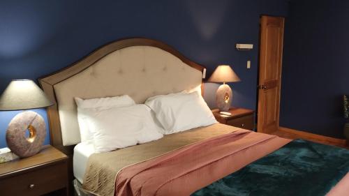 een slaapkamer met een bed met witte kussens en 2 lampen bij Casa Hacienda Santo Domingo in San Lucas Sacatepéquez