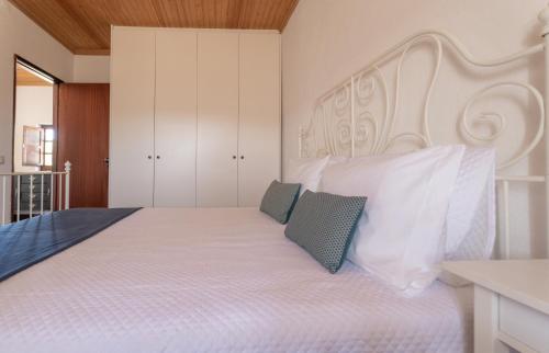 a bedroom with a large white bed with two pillows at Country House - Quinta das 3 Nogueiras in Abitureiras