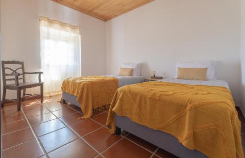 a bedroom with two beds and a chair and a window at Country House - Quinta das 3 Nogueiras in Abitureiras
