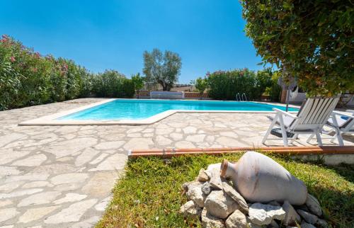 a swimming pool with a chair and a statue next to it at Country House - Quinta das 3 Nogueiras in Abitureiras
