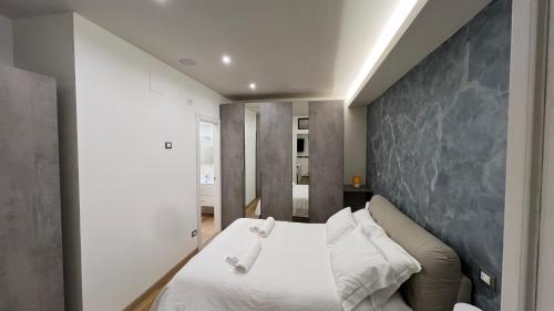 a bedroom with a white bed and a gray wall at Loft San Leopardo in Rieti