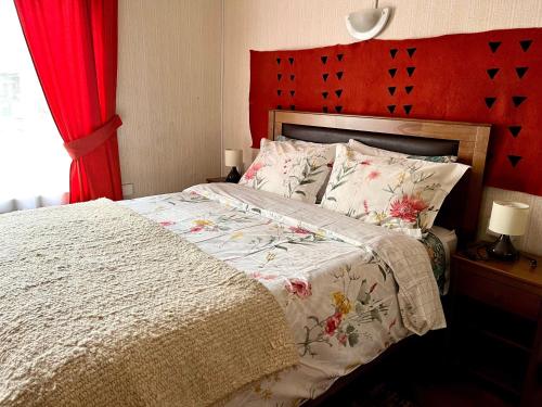 a bedroom with a large bed with a red headboard at Hostal siete colores, Melipeuco in Melipeuco