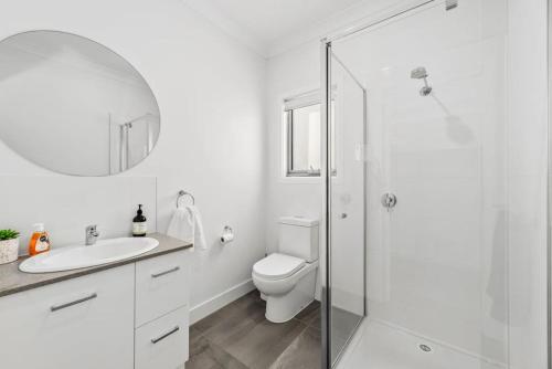 a white bathroom with a toilet and a sink at Nirvana Armstrong Creek Family Beach Home in Mount Duneed