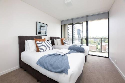 a bedroom with two beds and a large window at Sapphire of South Yarra - two bedroom condominium in Melbourne