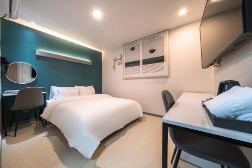 a bedroom with a white bed and a desk and a table at Hotel Centro Stay in Incheon