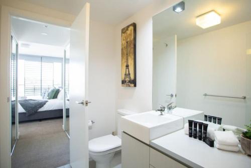 a bathroom with a sink and a toilet and a bed at Sapphire of South Yarra - two bedroom condominium in Melbourne
