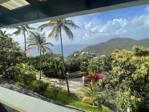 a view of the ocean and palm trees from a balcony at Guesthouse with amazing views in Marigot Bay