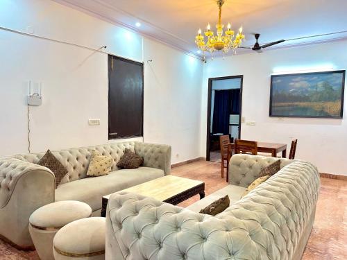 a living room with couches and a chandelier at spacious 4 bhk with hall and kitchen near Medanta in Gurgaon