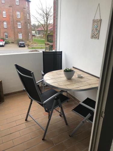 a table and chair on a balcony with a view of a street at Wolkenlos in Butjadingen
