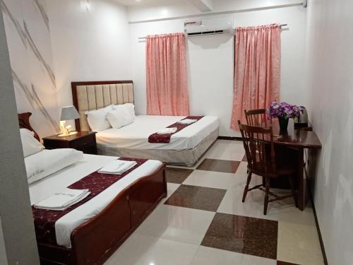 a bedroom with two beds and a desk and a table at Casa de Robles Tanay Rizal in Tanay