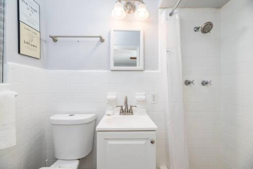 a white bathroom with a toilet and a sink at Ocean Breeze Paradise Apt 5A in Fort Lauderdale
